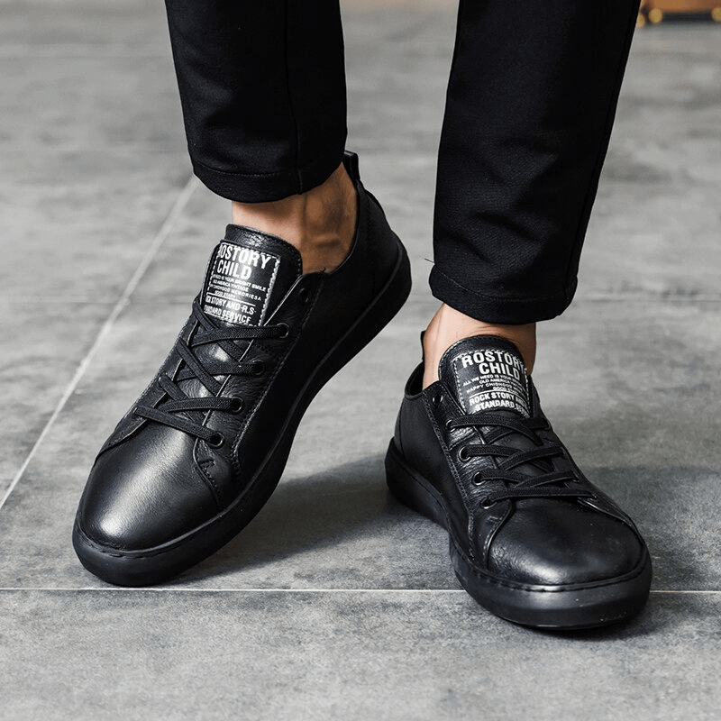 Man wearing stylish black leather walking shoes with breathable design and slip-on closure on gray floor, showcasing sleek look.
